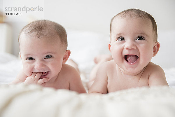 Kaukasische Zwillingsmädchen lächelnd auf dem Bett