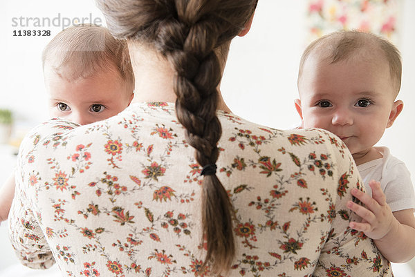 Kaukasische Mutter hält Zwillingstöchter im Arm