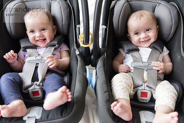 Kaukasische Zwillingsmädchen in Autositzen