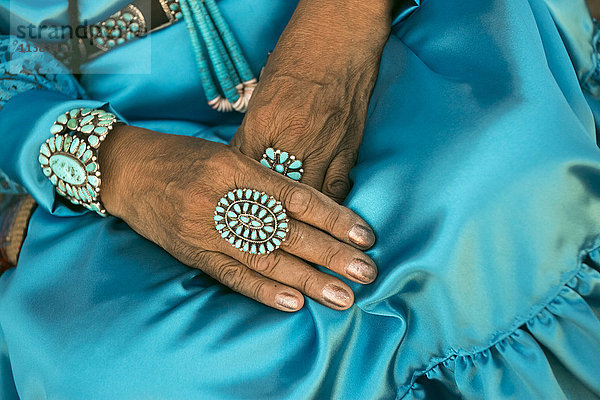 Schoß einer Frau mit traditionellem blauen Kleid und Ringen