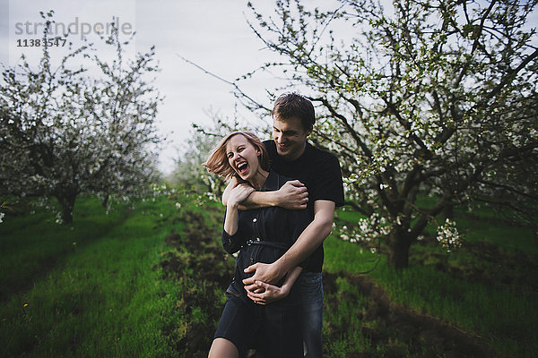 Kaukasisches Paar  das sich in der Nähe von Bäumen umarmt