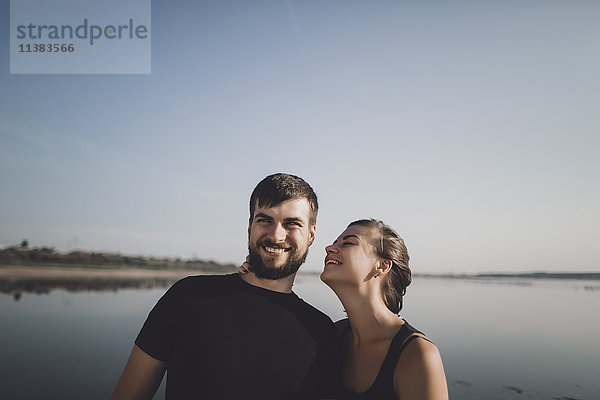 Lächelndes kaukasisches Paar in der Nähe eines Sees