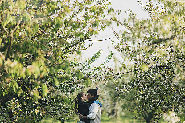 Kaukasisches Paar küsst sich in der Nähe von Bäumen