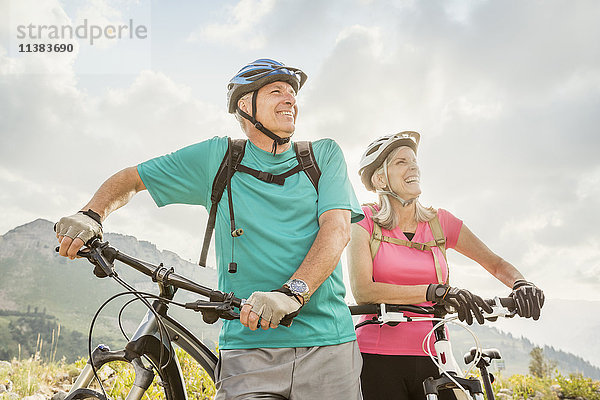 Stehendes kaukasisches Paar mit Mountainbikes