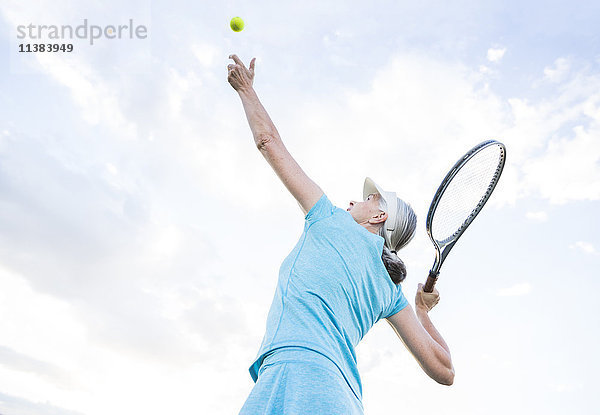 Kaukasische Frau serviert Tennisball