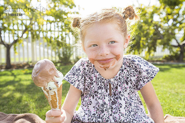 Kaukasisches Mädchen mit unordentlichem Gesicht isst Eiswaffel