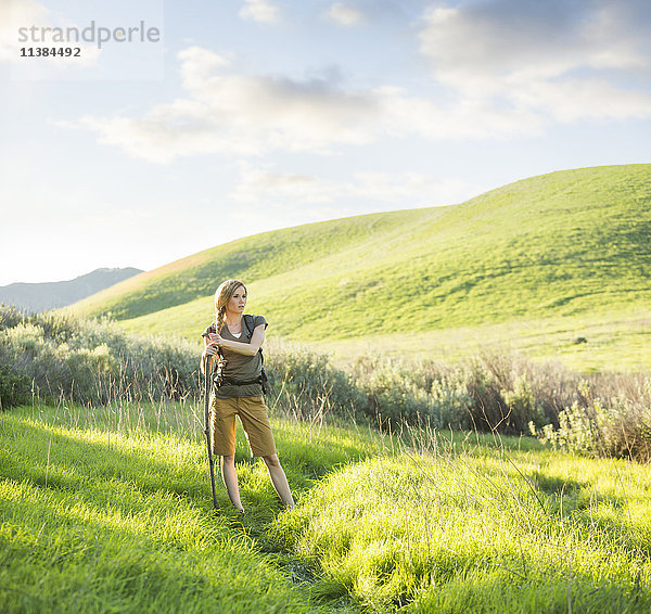 Kaukasische Frau mit Spazierstock auf einem Hügel