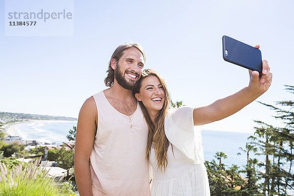Kaukasisches Paar posiert für Handy-Selfie am Strand