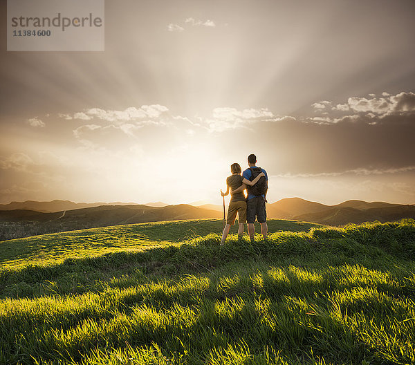 Paar umarmt auf Hügel bei Sonnenuntergang