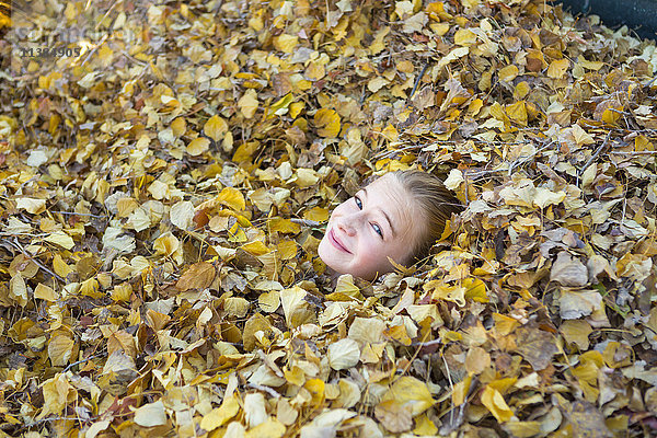 Gesicht eines kaukasischen Mädchens  das im Herbstlaub spielt