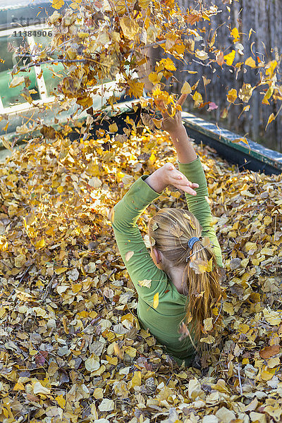 Kaukasisches Mädchen spielt im Herbstlaub