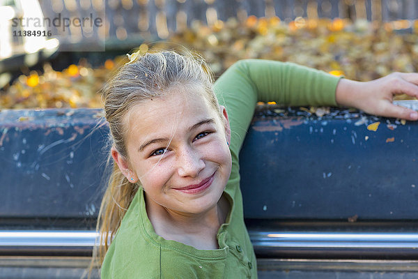 Kaukasisches Mädchen lächelnd in der Nähe von Herbstblättern in einem Lastwagen