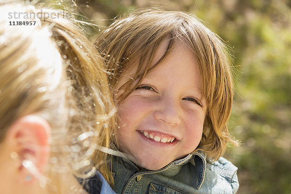 Porträt eines kaukasischen Jungen  der hinter seiner Schwester lächelt