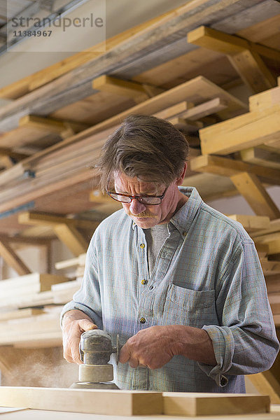 Kaukasischer Tischler beim Schleifen von Holz in der Werkstatt