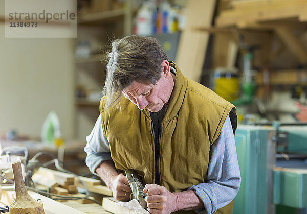 Kaukasischer Tischler beim Schleifen von Holz in der Werkstatt