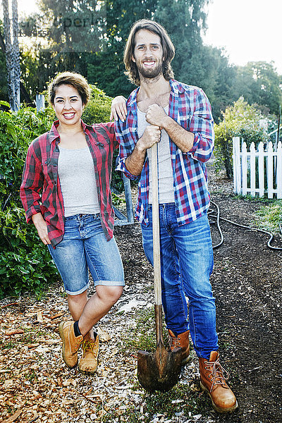 Porträt eines Paares  das mit einer Schaufel im Garten posiert