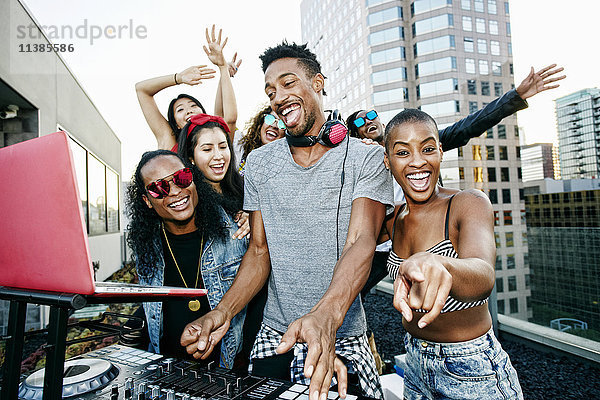 Freunde posieren mit DJ auf dem Dach der Stadt