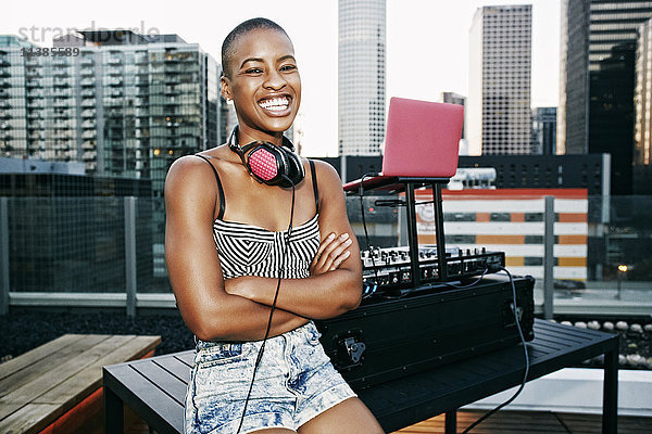 Lächelnder schwarzer DJ entspannt sich auf dem Dach eines Hauses