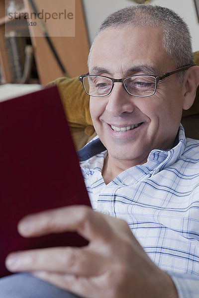 Lächelnder hispanischer Mann beim Lesen eines Buches