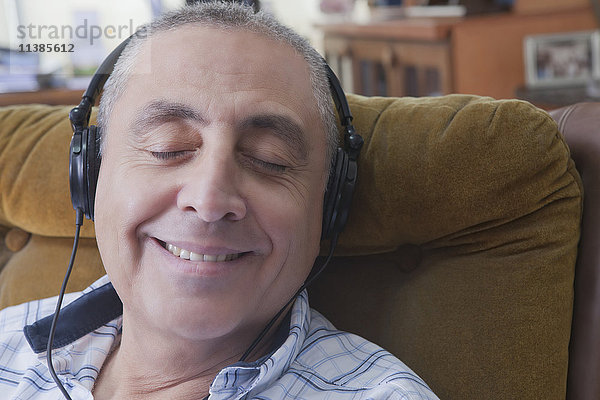 Lächelnder hispanischer Mann  der Kopfhörer hört