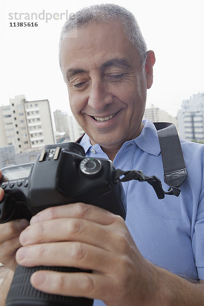 Hispanischer Mann  der ein Foto auf einer Digitalkamera untersucht