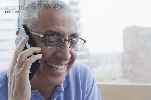Lächelnder hispanischer Mann  der mit einem Handy telefoniert