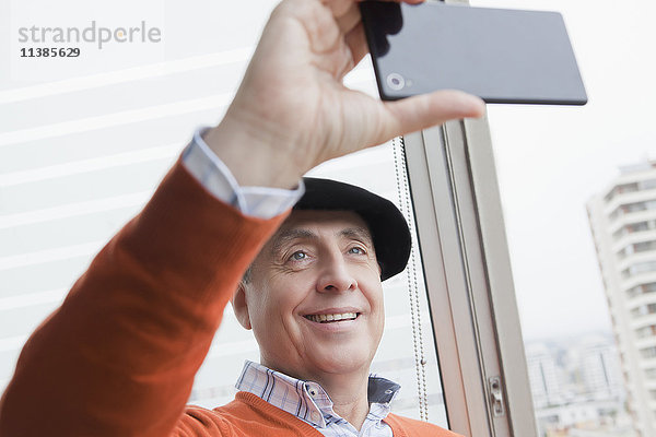 Lächelnder hispanischer Mann  der für ein Selfie mit seinem Handy posiert