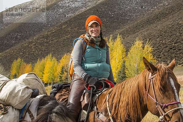 Lächelnde kaukasische Frau auf einem Pferd im Winter