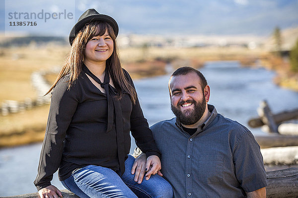 Lächelndes kaukasisches Paar posiert in der Nähe des Flusses