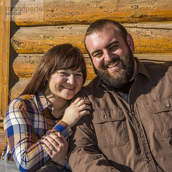 Kaukasisches Paar lächelnd in der Nähe der Blockhauswand
