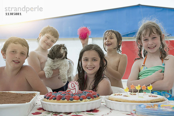 Lächelnde kaukasische Kinder posieren auf einer Geburtstagsfeier