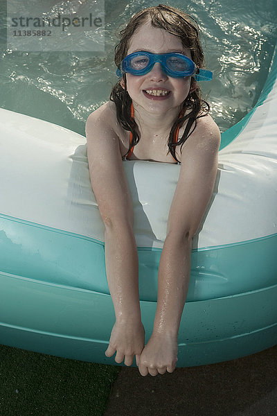 Lächelndes kaukasisches Mädchen im aufblasbaren Schwimmbecken