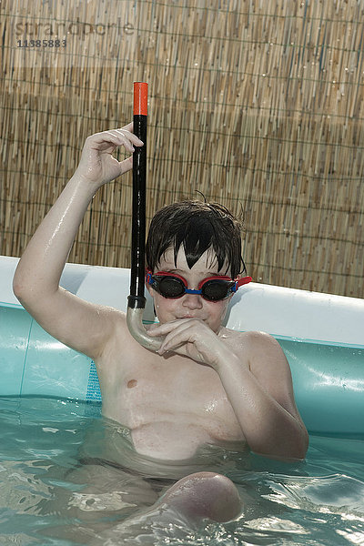 Kaukasischer Junge mit Schnorchel im aufblasbaren Schwimmbad