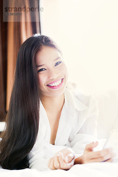 Porträt eines lächelnden asiatischen Teenager-Mädchens auf dem Bett