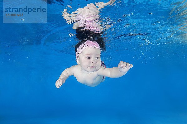 Kleinkindes Mädchen  das in einem Schwimmbad unter Wasser schwimmen lernt  Ukraine  Europa