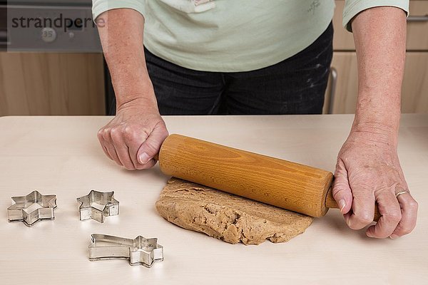 Frau rollt Teig für Weihnachtsplätzchen