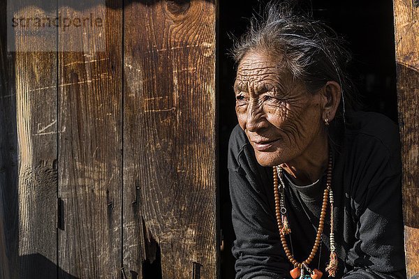 Ältere Bäuerin schaut aus dem Fenster  Ghyaru  Manang  Nepal  Asien