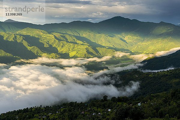 Nebel bedeckt den Phewa-See am Morgen  die umliegenden Hügel mit Bäumen sind von der Sonne beschienen  Sarangkot  Distrikt Kaski  Nepal  Asien
