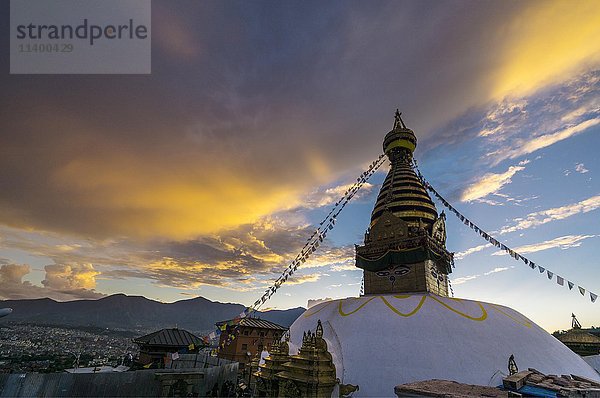 Stupa des Swayambhunath-Tempels  Affentempel  geschmückt mit tibetischen Gebetsfahnen  orangefarbene Wolken darüber  Kathmandu  Nepal  Asien