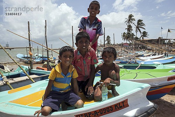 Einheimische Kinder sitzen auf einem Fischerboot im Hafen  Beruwela  Westprovinz  Sri Lanka  Asien