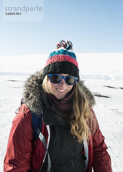 Junge Frau mit Winterjacke und Wollmütze  lächelnd  verschneite Landschaft  Island  Europa