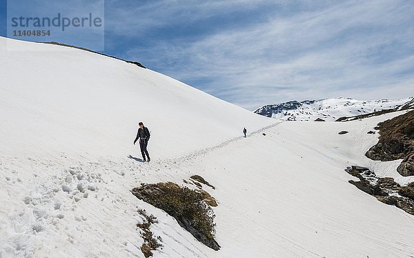 Zwei Wanderer überqueren Schneefeld  Berge  Rohrmoos Obertal  Schladminger Tauern  Schladming  Steiermark  Österreich  Europa