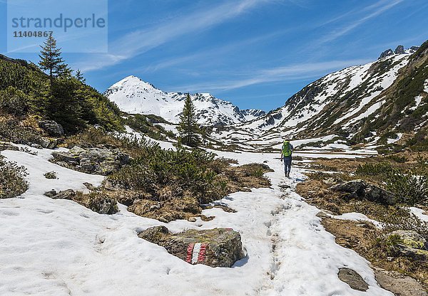 Junger Mann  Wanderer in Berglandschaft mit Schneeresten  Rohrmoos Obertal  Schladminger Tauern  Schladming  Steiermark  Österreich  Europa