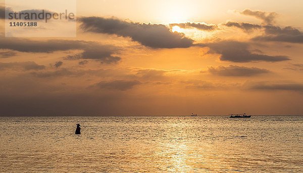 Sonnenuntergang über dem Meer  Fischer im Wasser stehend  im Gegenlicht  Lovina Beach  Bali  Indonesien  Asien