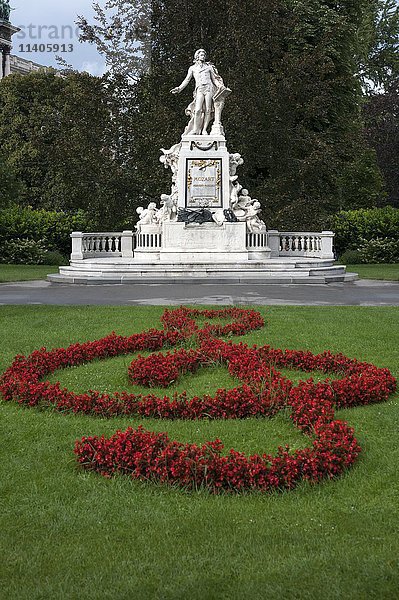 Rote Blumen als Geigentaste angeordnet mit Mozart-Denkmal  Schlossgarten  Wien  Österreich  Europa