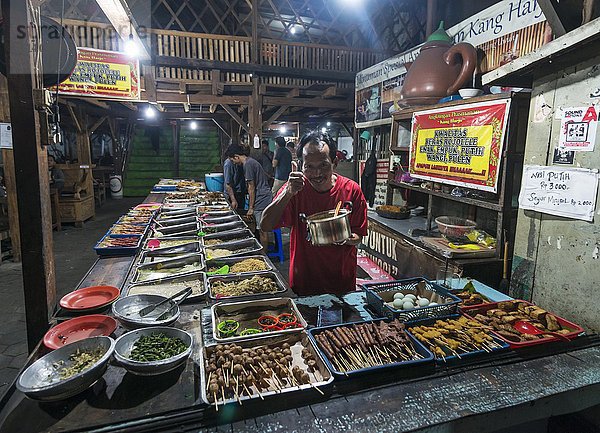 Indonesisches Essen am Stand  fröhlicher Verkäufer  Daumen hoch  Lebensmittelmarkt  Yogyakarta  Java  Indonesien  Asien