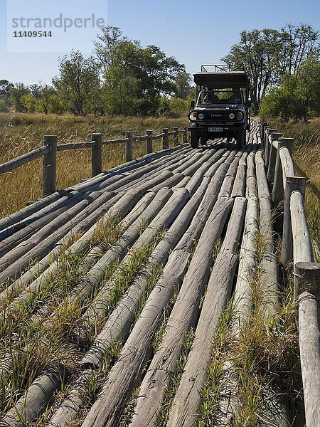 Geländewagen fährt über Holzbrücke  Okavango-Delta  Botswana  Afrika