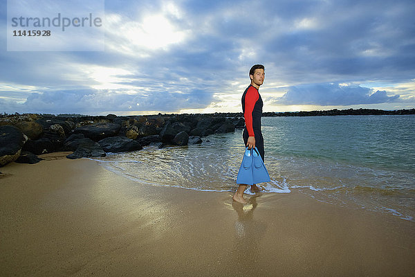 Ein Mann geht vom Lydgate Beach mit Schwimmflossen ins Wasser; Kauai  Hawaii  Vereinigte Staaten von Amerika'.
