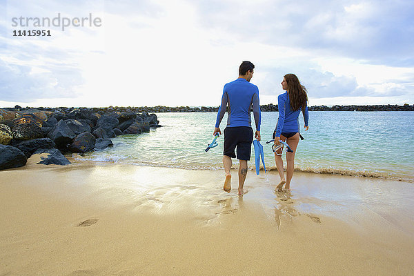 Ein Paar geht am Lydgate Beach mit Flossen und Schnorchelausrüstung ins Wasser; Kauai  Hawaii  Vereinigte Staaten von Amerika'.