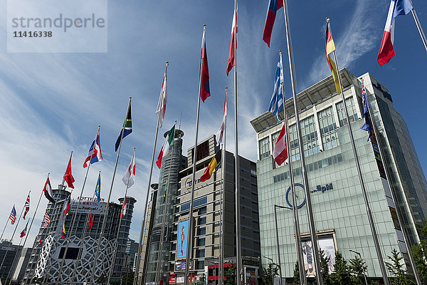 Moderne Gebäude mit digitalen Bildschirmen für Werbung und internationalen Flaggen auf Masten in einer Reihe; Seoul  Südkorea